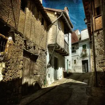Calle del Cristo con casas tradicionales de piedra y madera en El Arenal, Ávila.