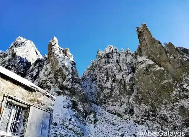 Vista contrapicada de los escarpados picos graníticos de Los Galayos cubiertos parcialmente de nieve.